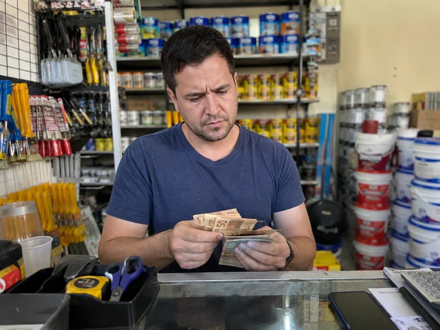 Comerciante contando notas de dinheiro com expressão de dúvida